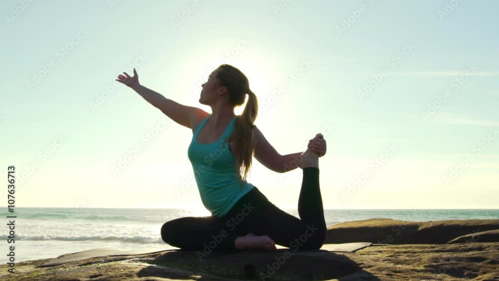 Happy young woman practicing yoga on the beach at sunset. Healthy active lifestyle concept. Slow Motion