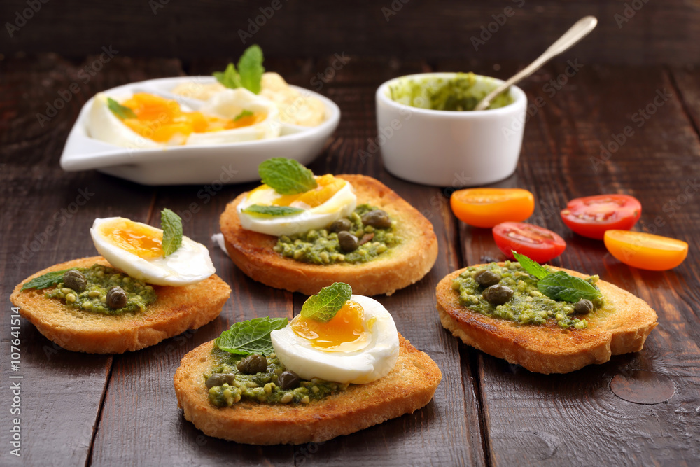Fresh toasts with pesto and egg on wooden background Fresh toasts with pesto and egg on wooden background