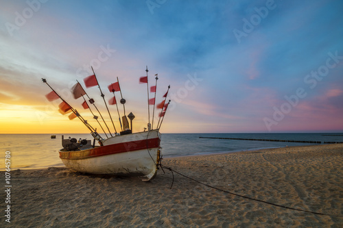 Fototapeta fishing boat on the sea shore in the light of the setting sun