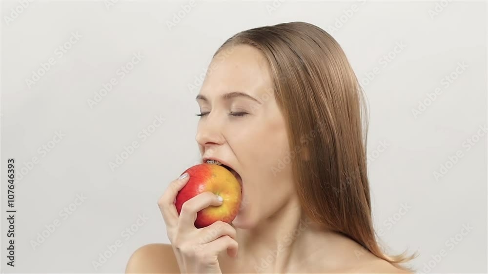 Blonde girl with braces eating apple. White. Closeup. Slow motion Blonde girl with braces eating apple. White. Closeup. Slow motion