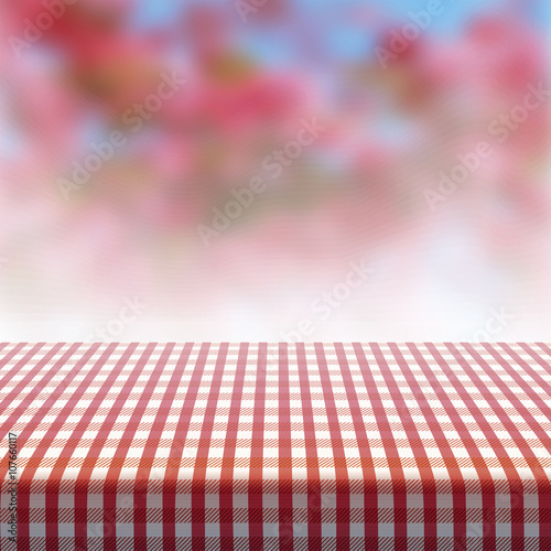 Vector picnic table covered with tablecloth on blurred background.