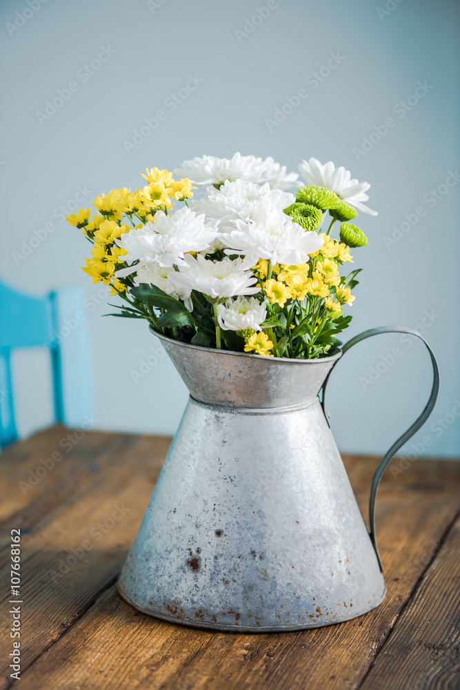 Fresh summer flowers in rustic vase, on wooden table