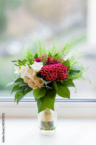 Fototapeta Naklejka Na Ścianę i Meble -  Wedding bouquet on window sill. Bride's traditional symbolic accessory. Floral composition with red celosia flowers.