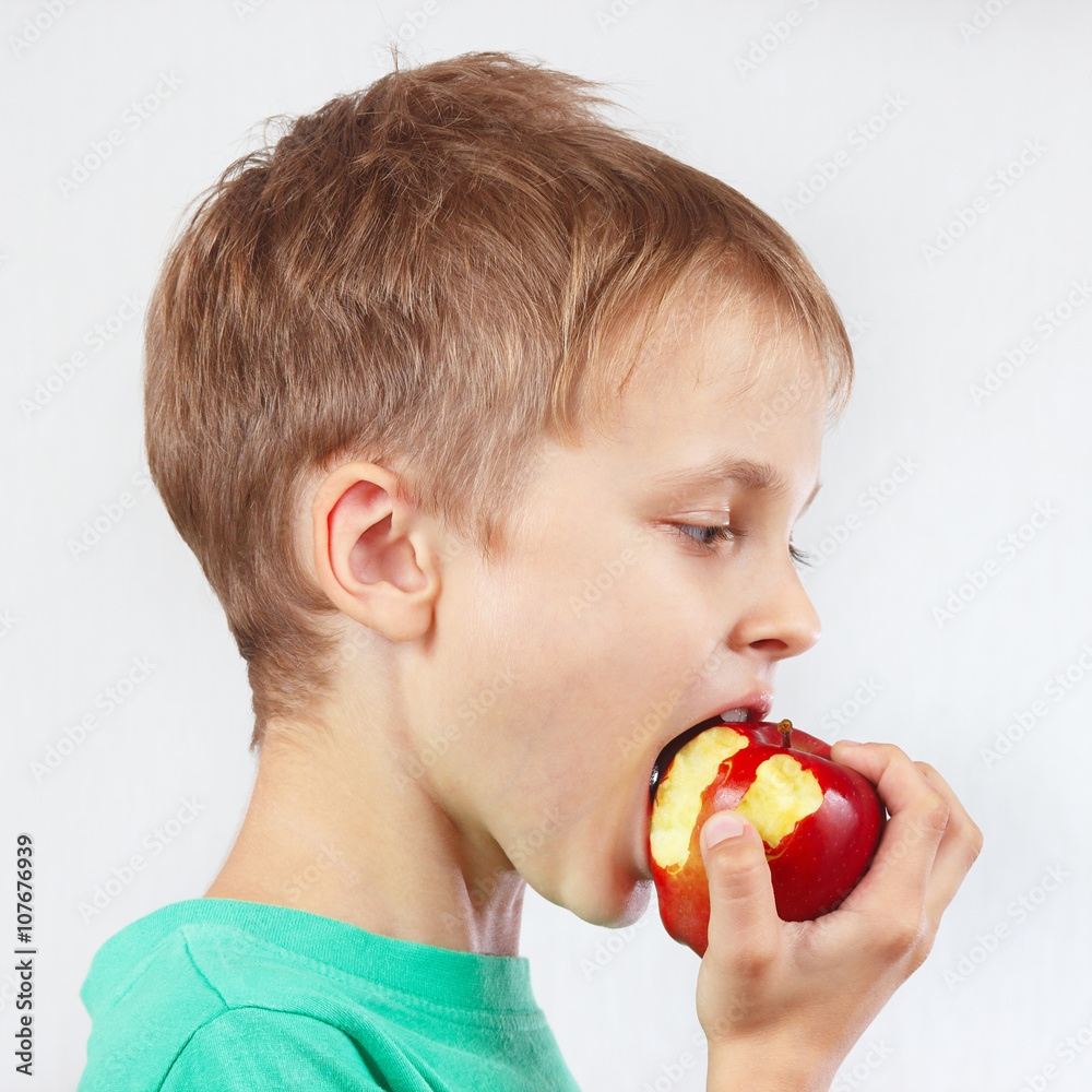 Young boy in a green shirt eating a juicy red apple Young boy in a green shirt eating a juicy red apple