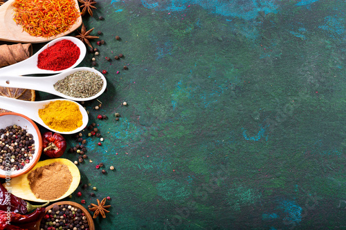 Fototapeta Naklejka Na Ścianę i Meble -  various spices in spoons on old green background