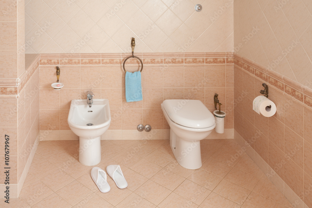 Fototapeta premium Slippers Near Bidet In Home Bathroom