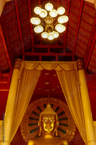 Buddha with golden halo under huge candelabrum