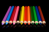 colored pencils isolated on black background with reflection