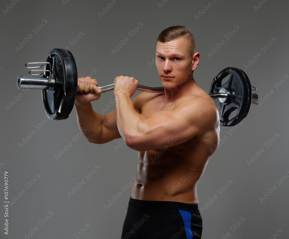 Shirtless muscular man holds barbell.