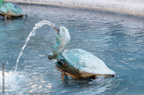 Color DSLR stock image of a green, bronze turtle fountain spraying water. Horizontal with copy space for text