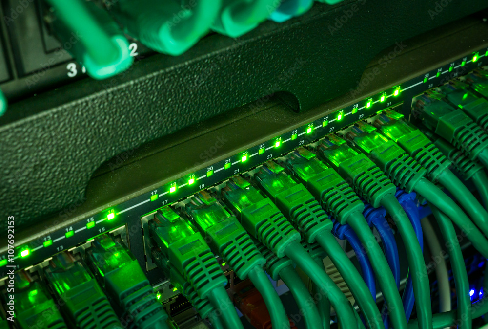 Close up of green network cables connected to switch glowing in the dark