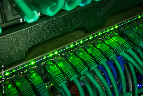 Close up of green network cables connected to switch glowing in the dark