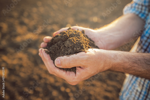 Farmer holding pile of arable soil in hands photo