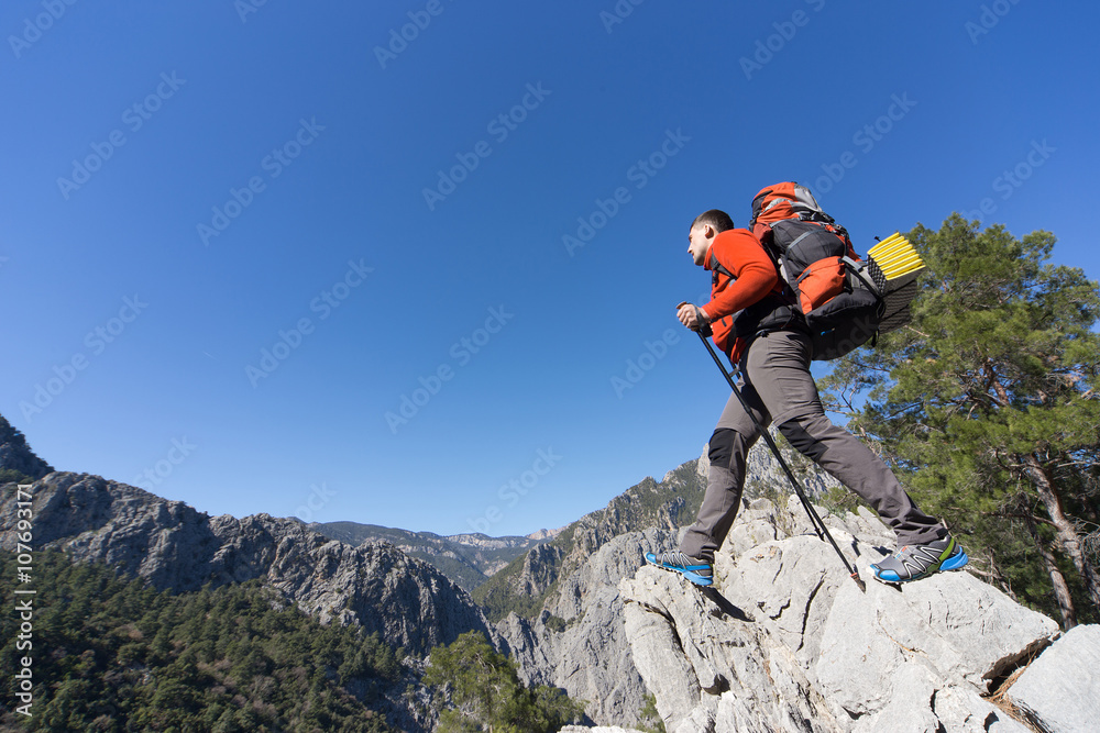 Young man with backpack on a mountain top on a sunny day.