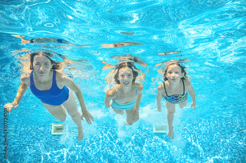 Family swims in pool under water, happy active mother and children have fun underwater, kids sport on family vacation
