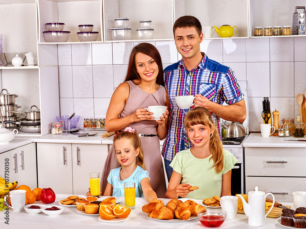 Parents prepare  breakfast for child. Big family with two kids having breakfast in the white kitchen. Happy family and children.