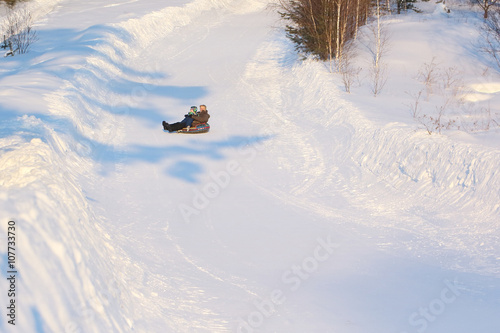 The man with the little boy riding a snow tubing  from the snow