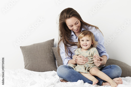 Smiling girl with her mother on bed