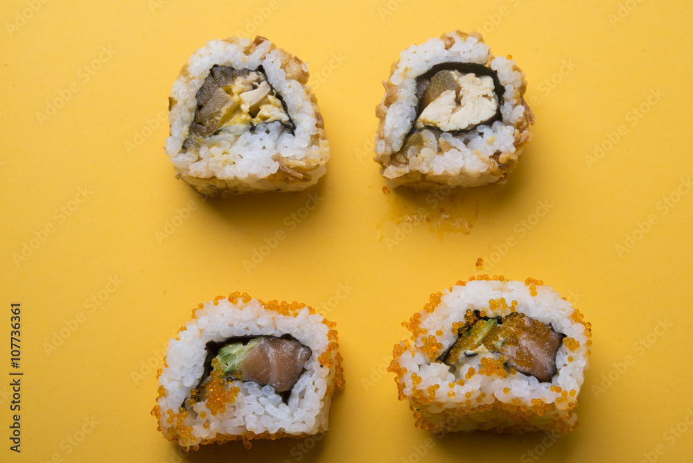 Various kinds of sushi food served on yellow blackground Various kinds of sushi food served on yellow blackground