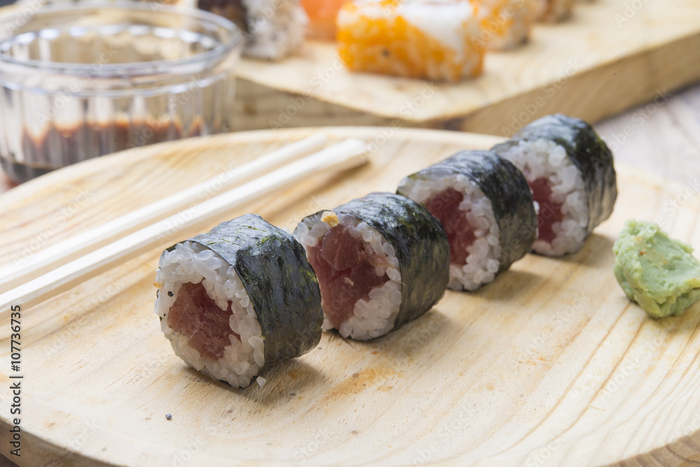 Different Sushi rolls,wasabi and ginger on a plate on wooden bac Different Sushi rolls,wasabi and ginger on a plate on wooden bac