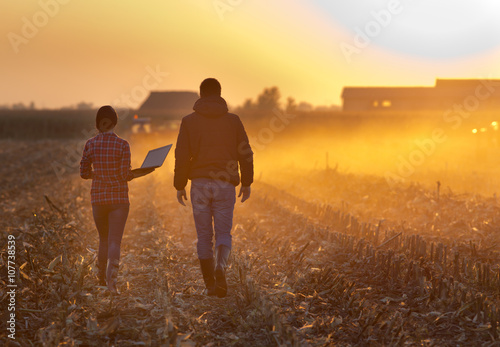 Obraz na plátně Farmers walking on field during baling