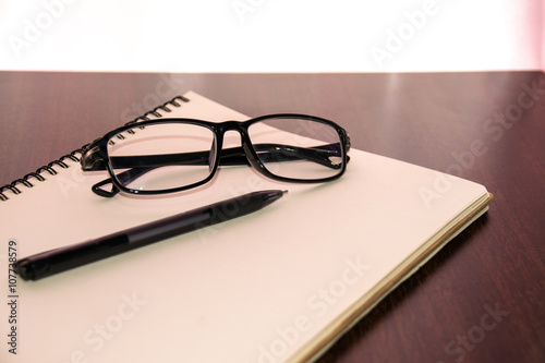 Close up Glasses and pen on notebook on table