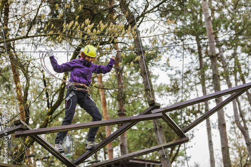 Fototapeta Naklejka Na Ścianę i Meble -  Woman on cables in an adventure park on a difficult course