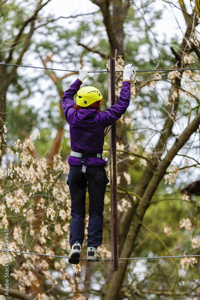 Woman on cables in an adventure park on a difficult course Woman on cables in an adventure park on a difficult course