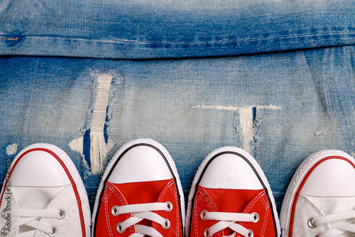 White and red sneakers on a the ripped denim background closeup.