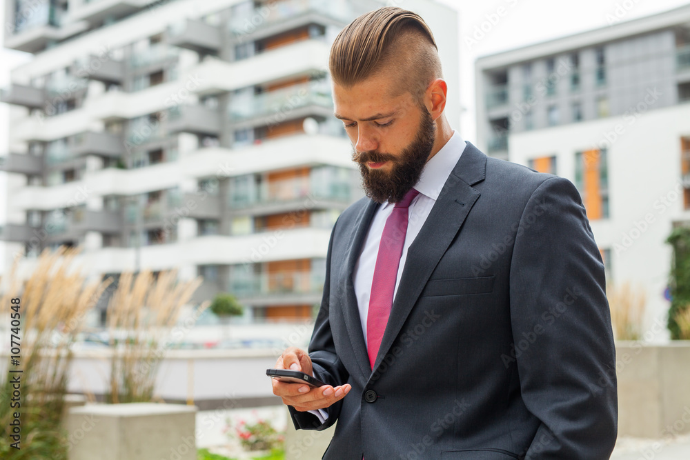 Young bearded businessman writting business e-mail using his mob Young bearded businessman writting business e-mail using his mob