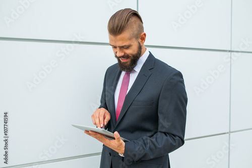 Young bearded businessman writting business e-mail using his tab