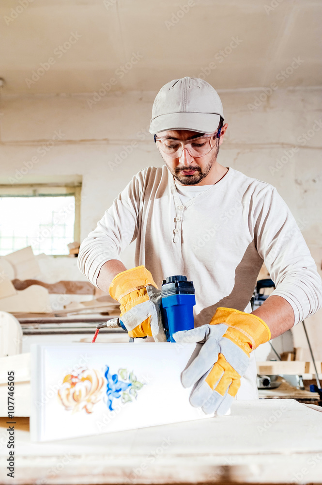 Carpenter working assembling a drawer with a screwdriver, he is wearing safety glasses protection Carpenter working assembling a drawer with a screwdriver, he is wearing safety glasses protection