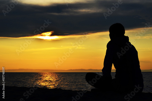 Girl sitting on the shore of the lake