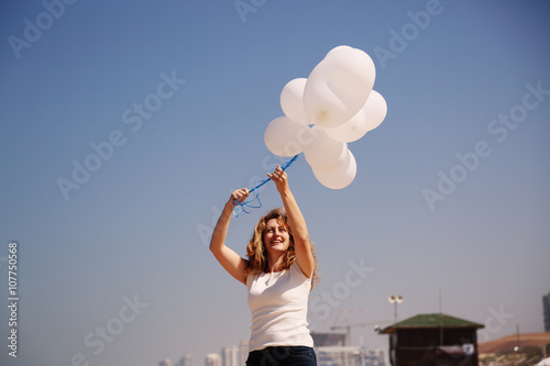 Beautiful redhead woman holding white balloons © dubova