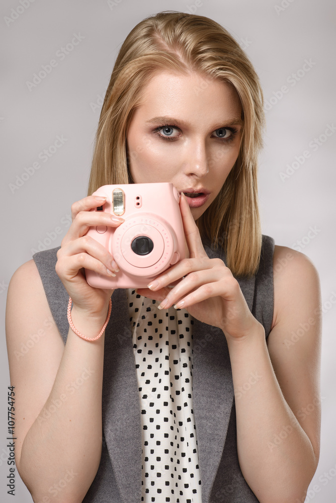 Beautiful blonde girl with pink camera laughs and smiles Beautiful blonde girl with pink camera laughs and smiles