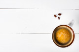 Coffee cup top view on white wooden table background. Flat lay cup of coffee and three coffee beans. Copy space.