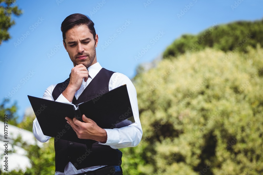 Handsome waiter looking at the menu
