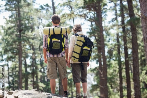 Rear view of couple standing on rock while hiking 