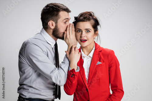 Photography Young man telling gossips to his woman colleague at the office