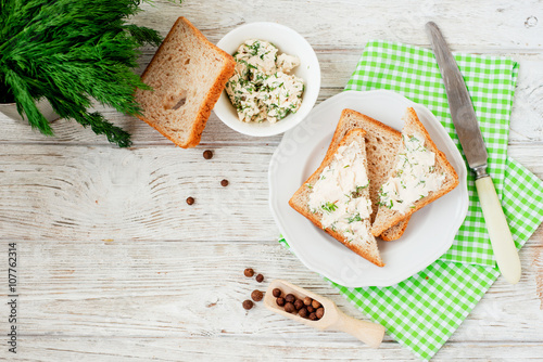
breakfast or lunch , light sandwiches ,  rye toast with cream cheese , dill and spices on a wooden background
