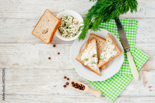 
breakfast or lunch , light sandwiches ,  rye toast with cream cheese , dill and spices on a wooden background
