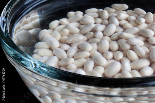 Closeup on white beans soaked in water in glass bowl