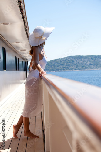 femme en maillot et paréo blanc sur le pont d'un bateau en mer © plprod