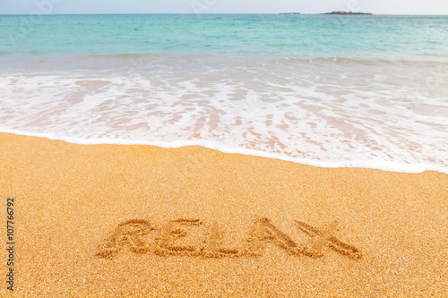 Inscription "RELAX" made on the beach by the blue sea