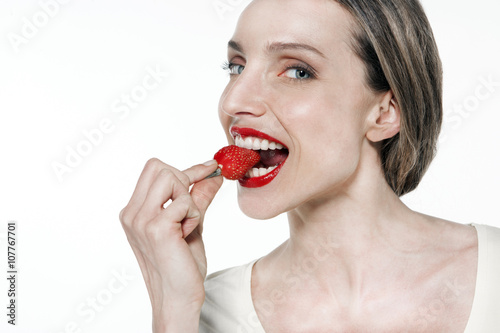 Portrait of a young Caucasian woman eating a strawberry