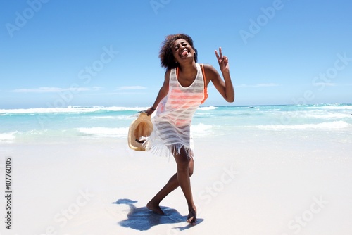 Cheerful attractive young african woman enjoying walk on beach