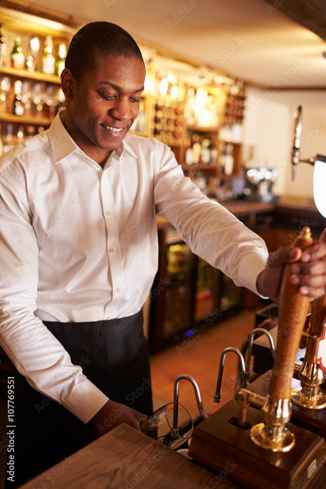 A young black man working behind a bar preparing drinks A young black man working behind a bar preparing drinks