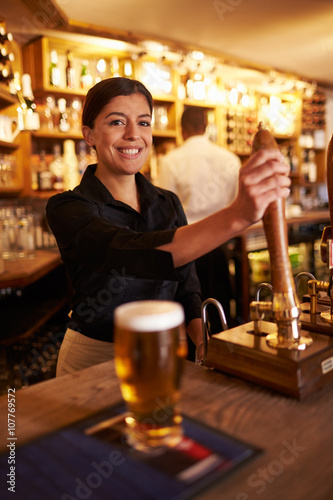 Φωτογραφία A young woman working behind a bar looking to camera