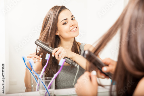 Woman using a flat iron in her hair