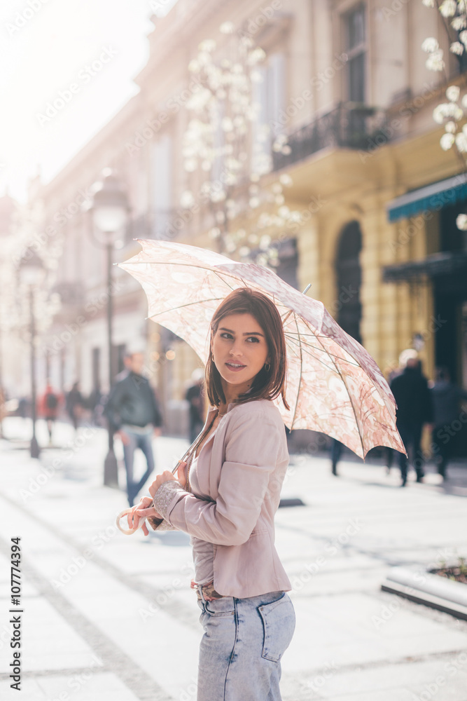 Young beautiful woman standing at the street with parasol

